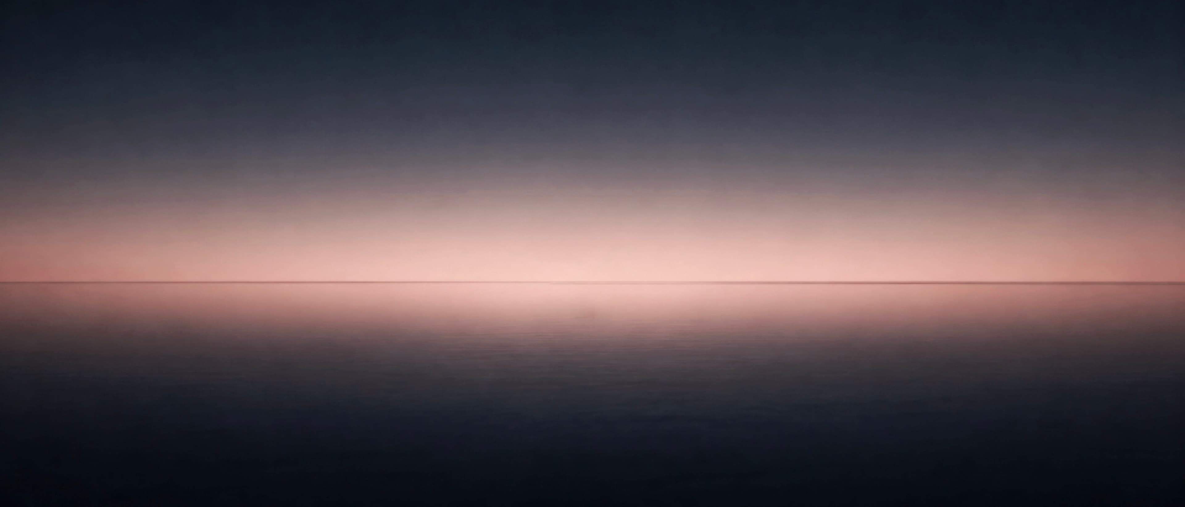Minimal dusk horizon over still water with a soft rose glow